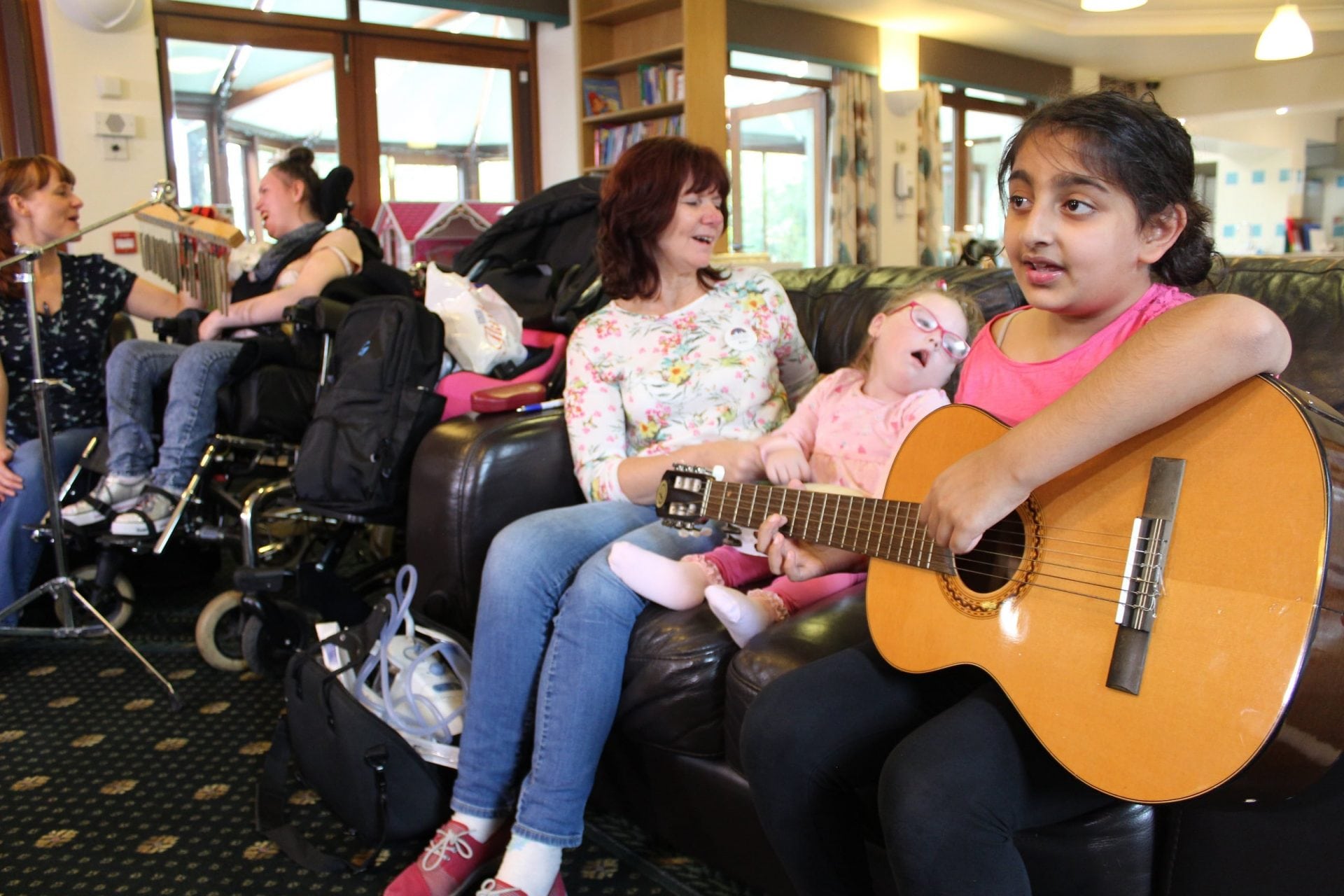 Girl playing guitar with other children and young people in Francis House