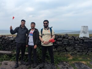 A group of three men holding flags stood on the top of a hill