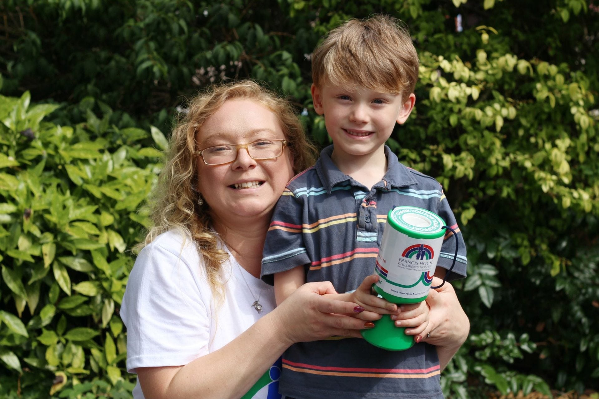 Volunteer Helen and son Thomas holding collection tin