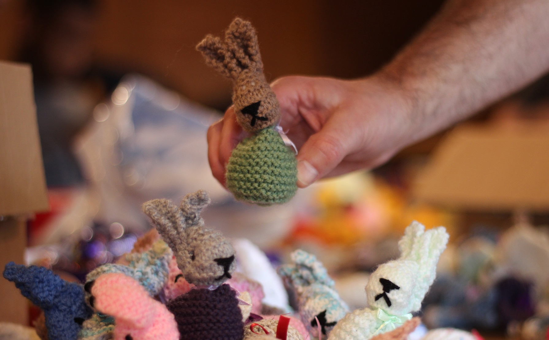 Hand places down knitted bunny in pile