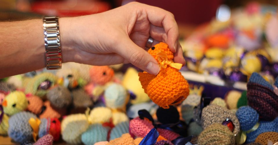Hand picking up knitted chick.
