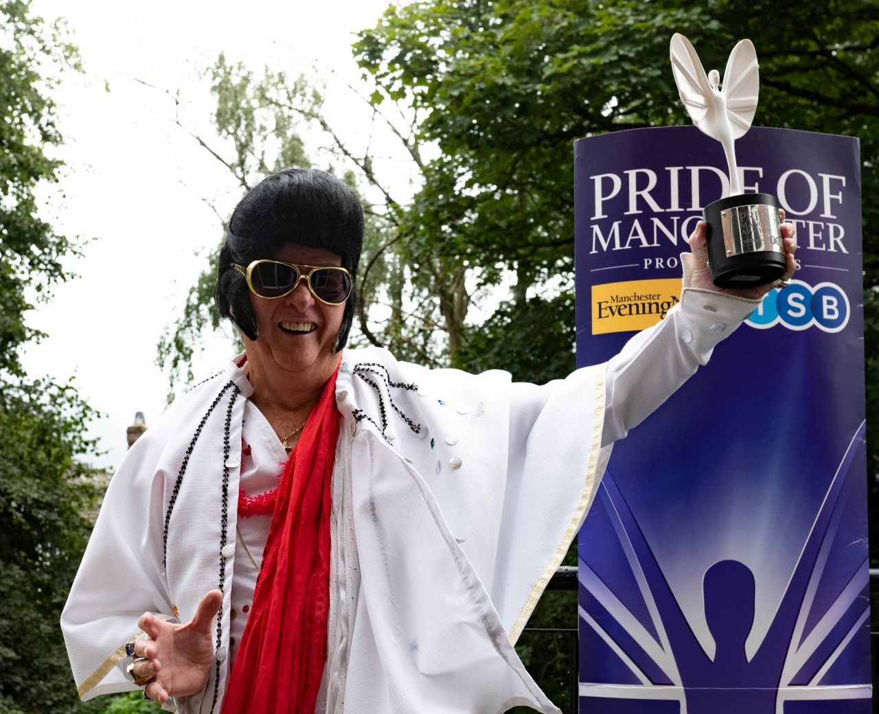 Jim Nicholas holding up Pride of Manchester Award