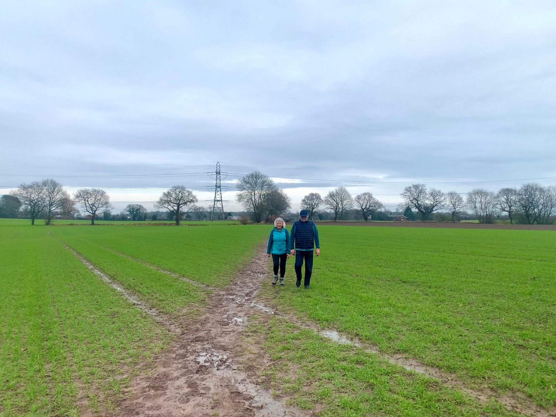 Pair cross a muddy field on the Lymm Loop