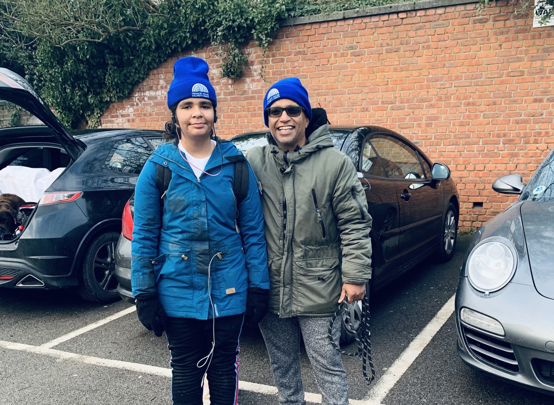 Father and daughter wearing winter clothes stood in car park