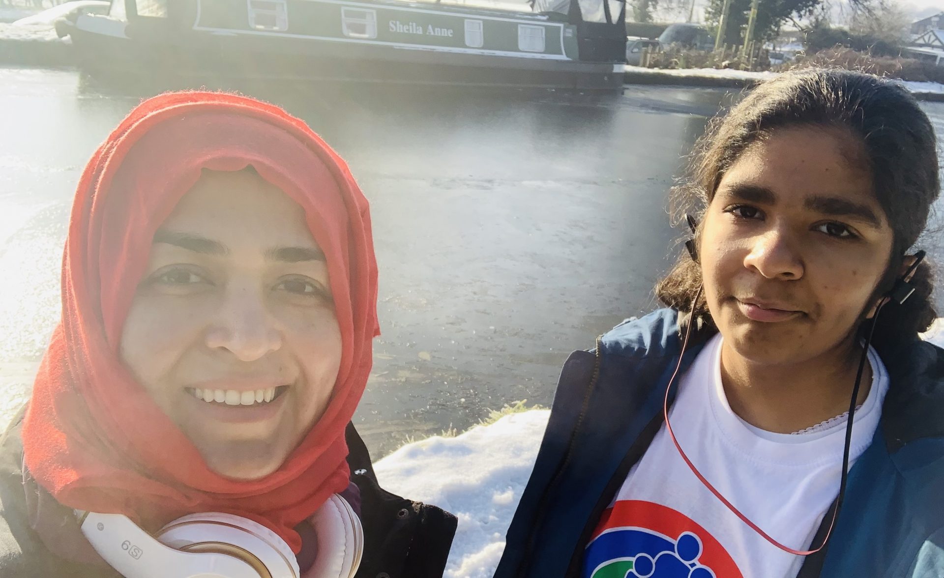 Mother and daughter smiling stood by frozen canal