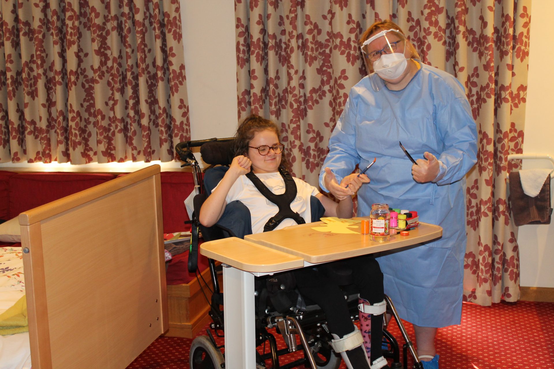 Child and nurse Dawn Geddes in PPE painting at Francis House.