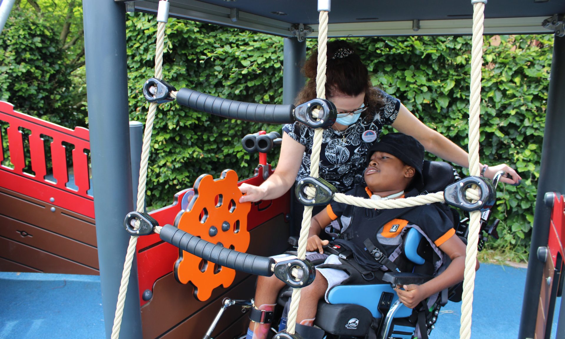Child in wheelchair with nurse in garden pirate ship at Francis House