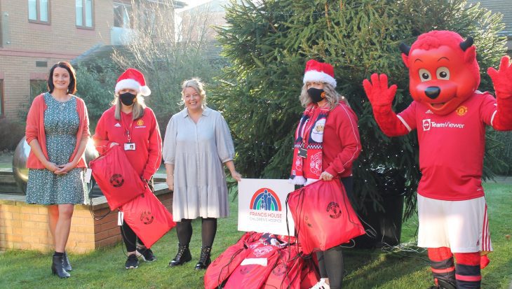 Manchester United Foundation staff holding Christmas sacks with Francis House staff