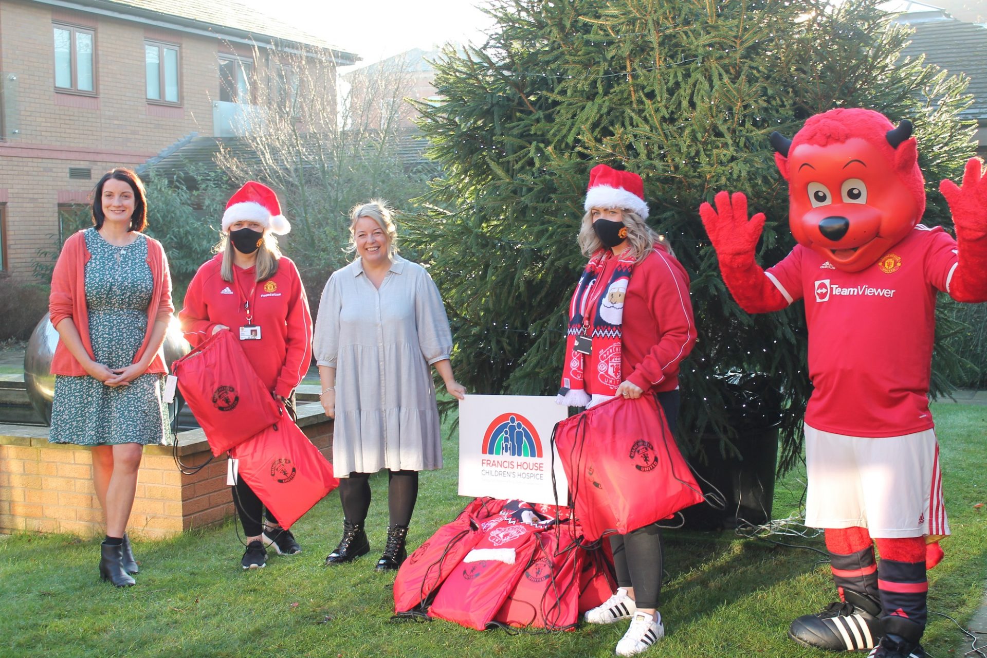 Manchester United Foundation staff holding Christmas sacks with Francis House staff