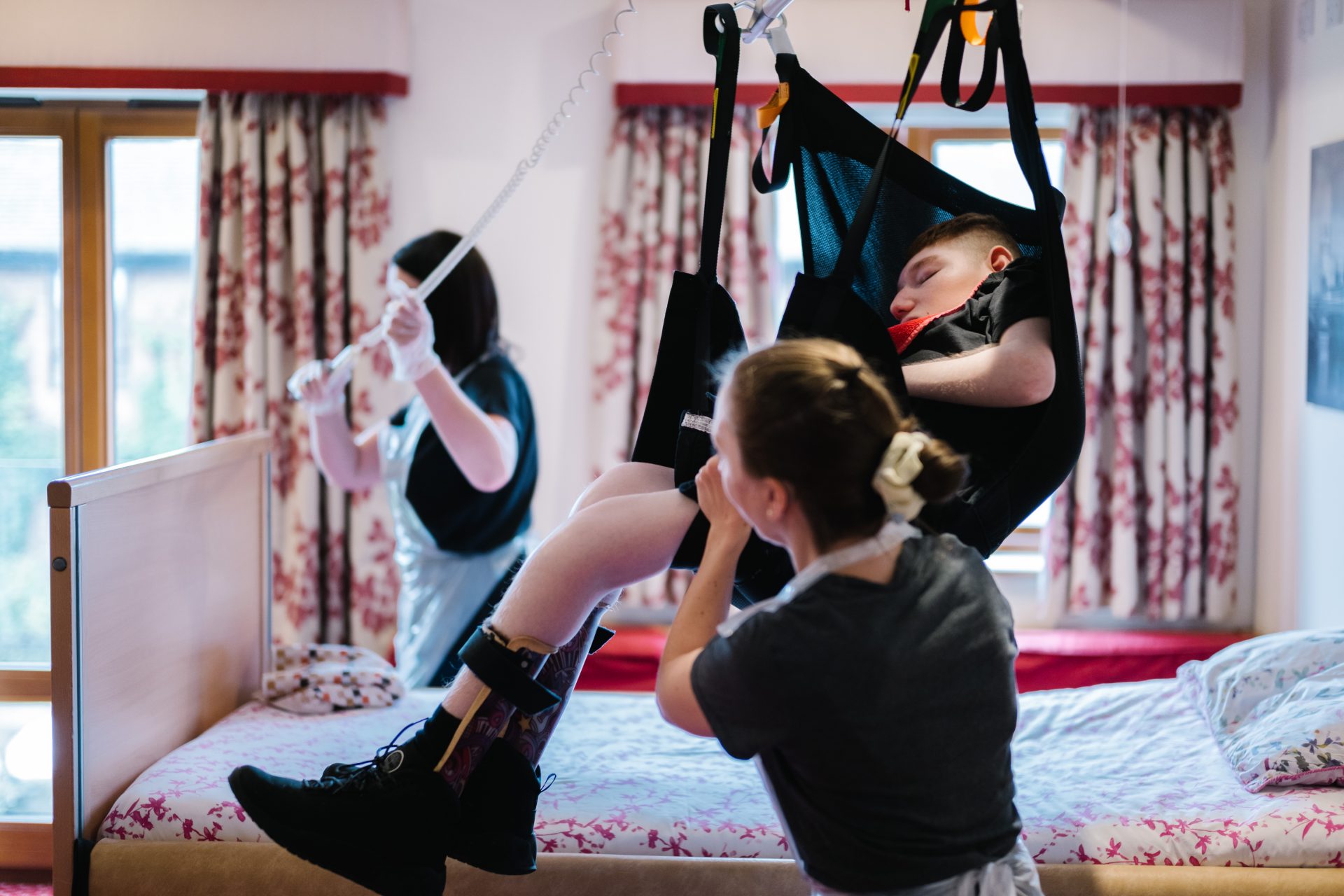 Young person being lifted in a hoist with two nurses