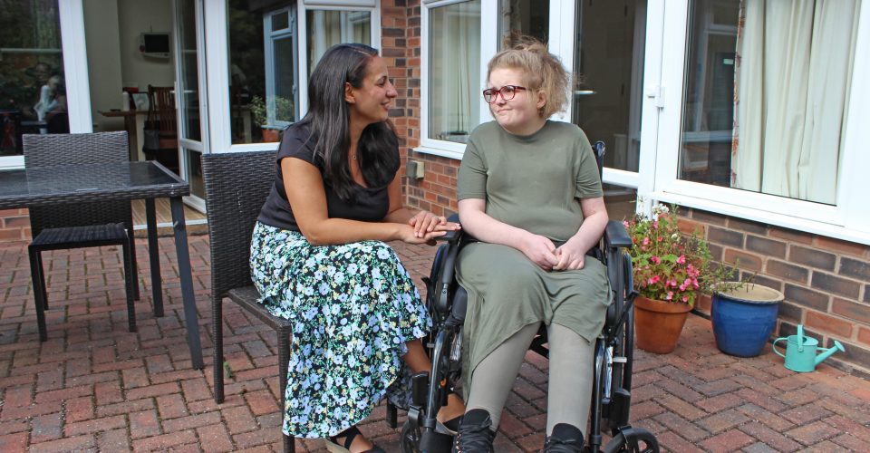 Woman seated speaking to a young person in a wheelchair