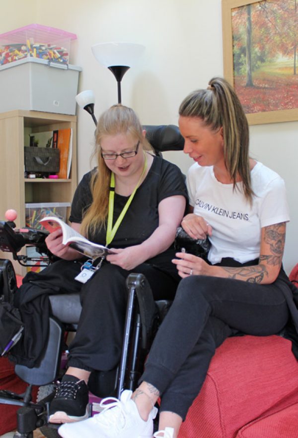 Woman in a wheelchair reading a book with other woman