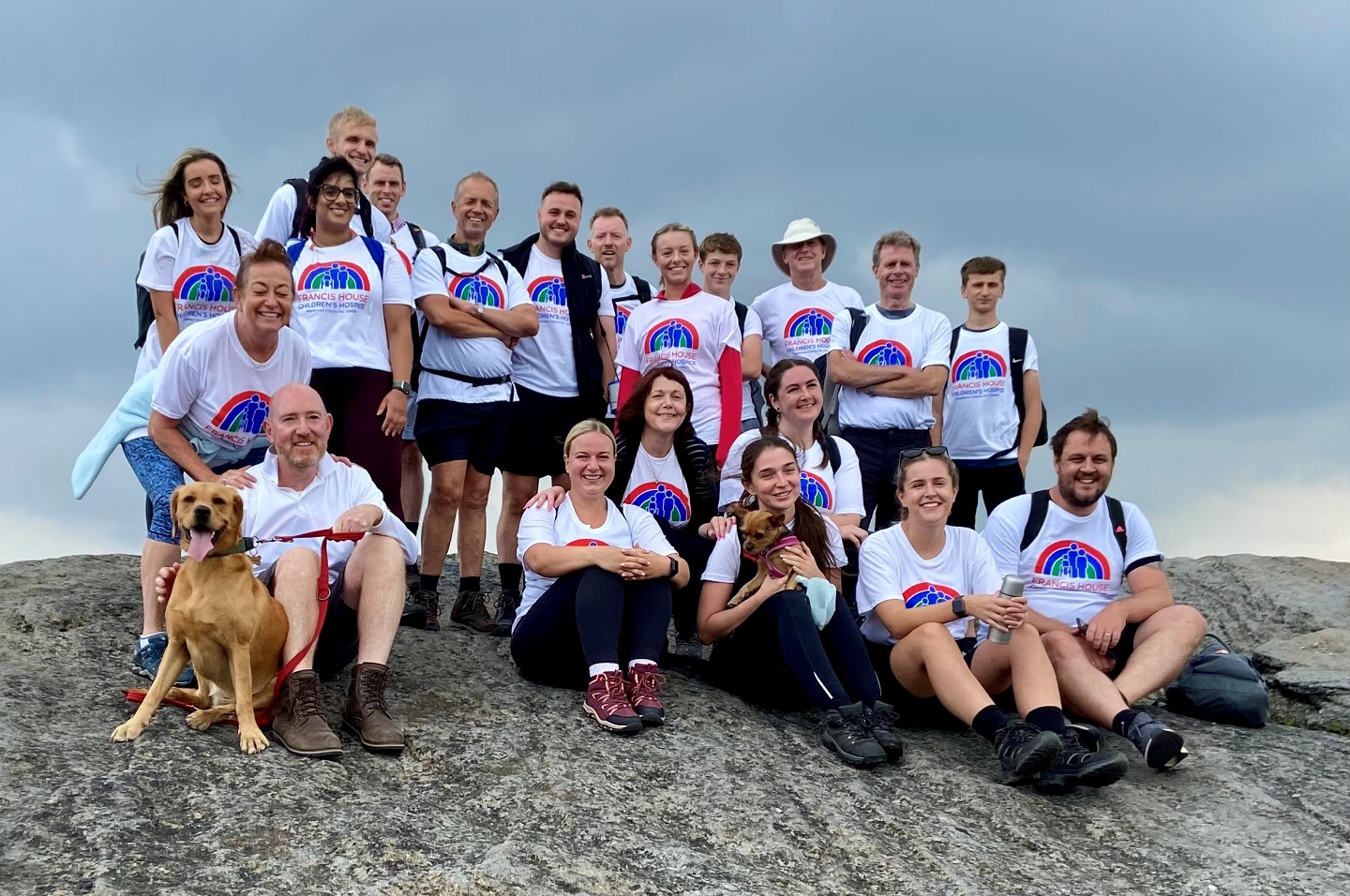 Group of people and dogs on a hill top rock