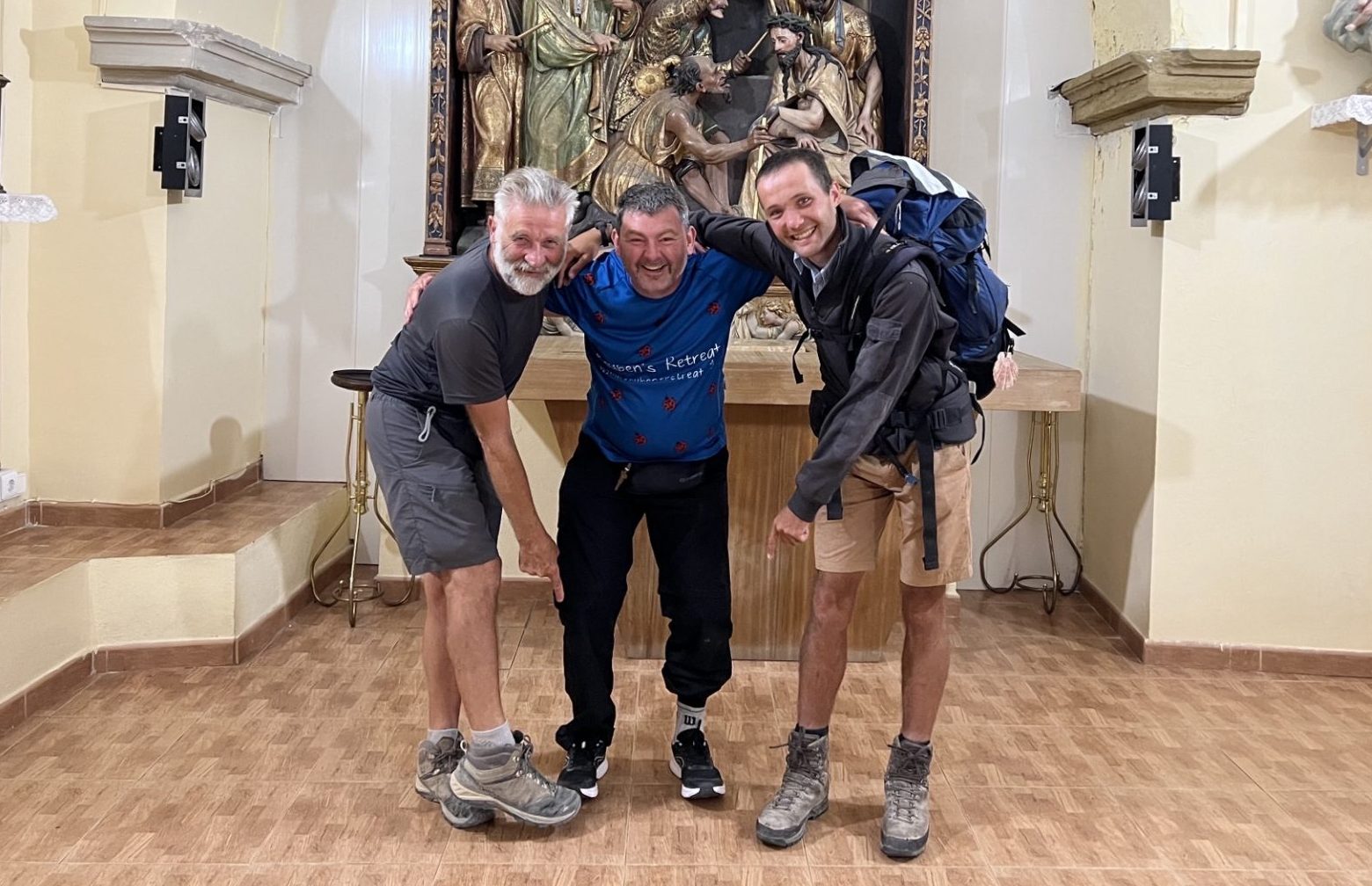 Three men stood in a monastery pointing at shoes
