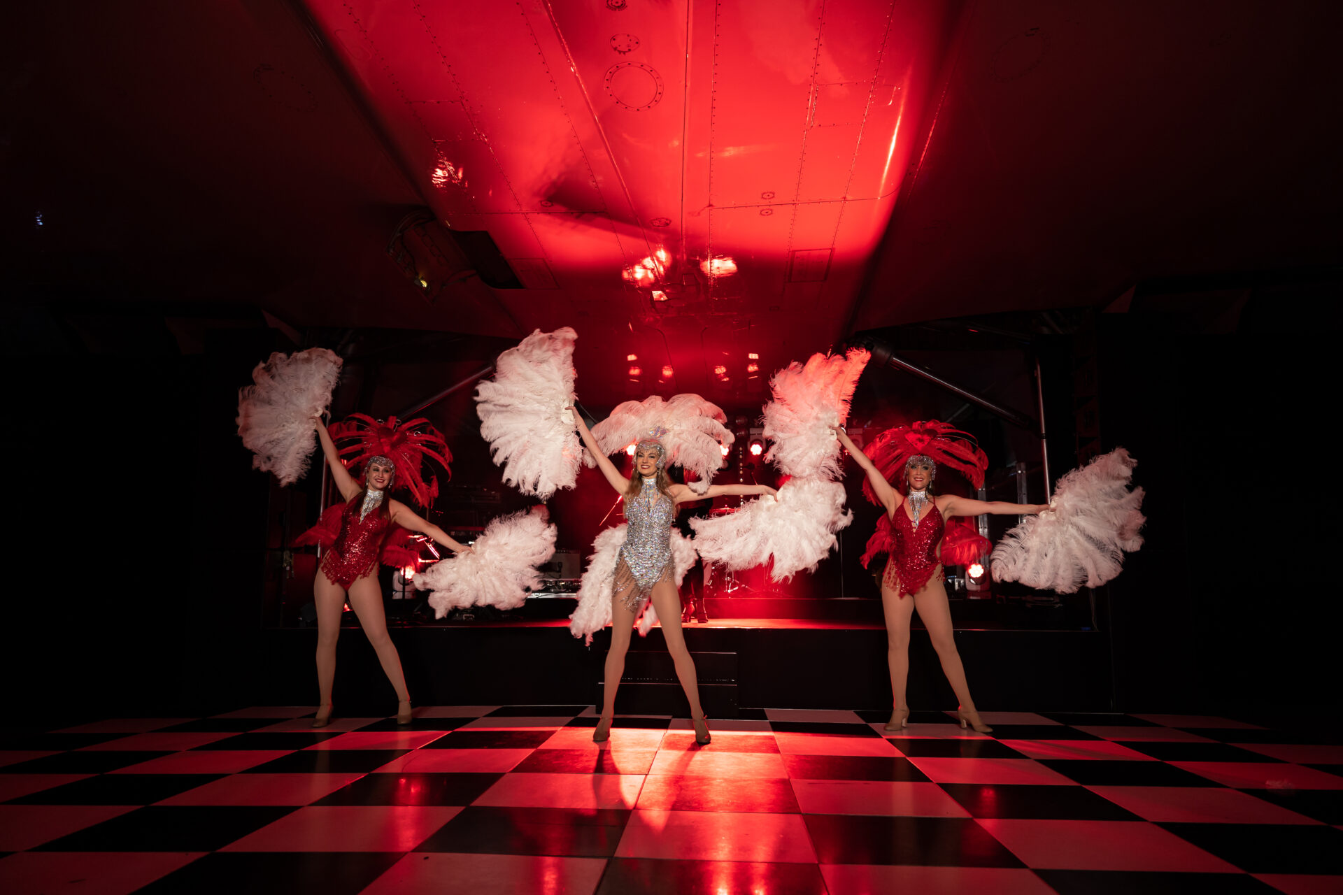 Three dancers holding feather boas on a stage