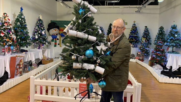 Man holding Christmas tree in a shop