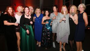 Women dressed in evening wear smiling at the camera