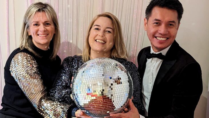 Three people stood holding a glitter ball