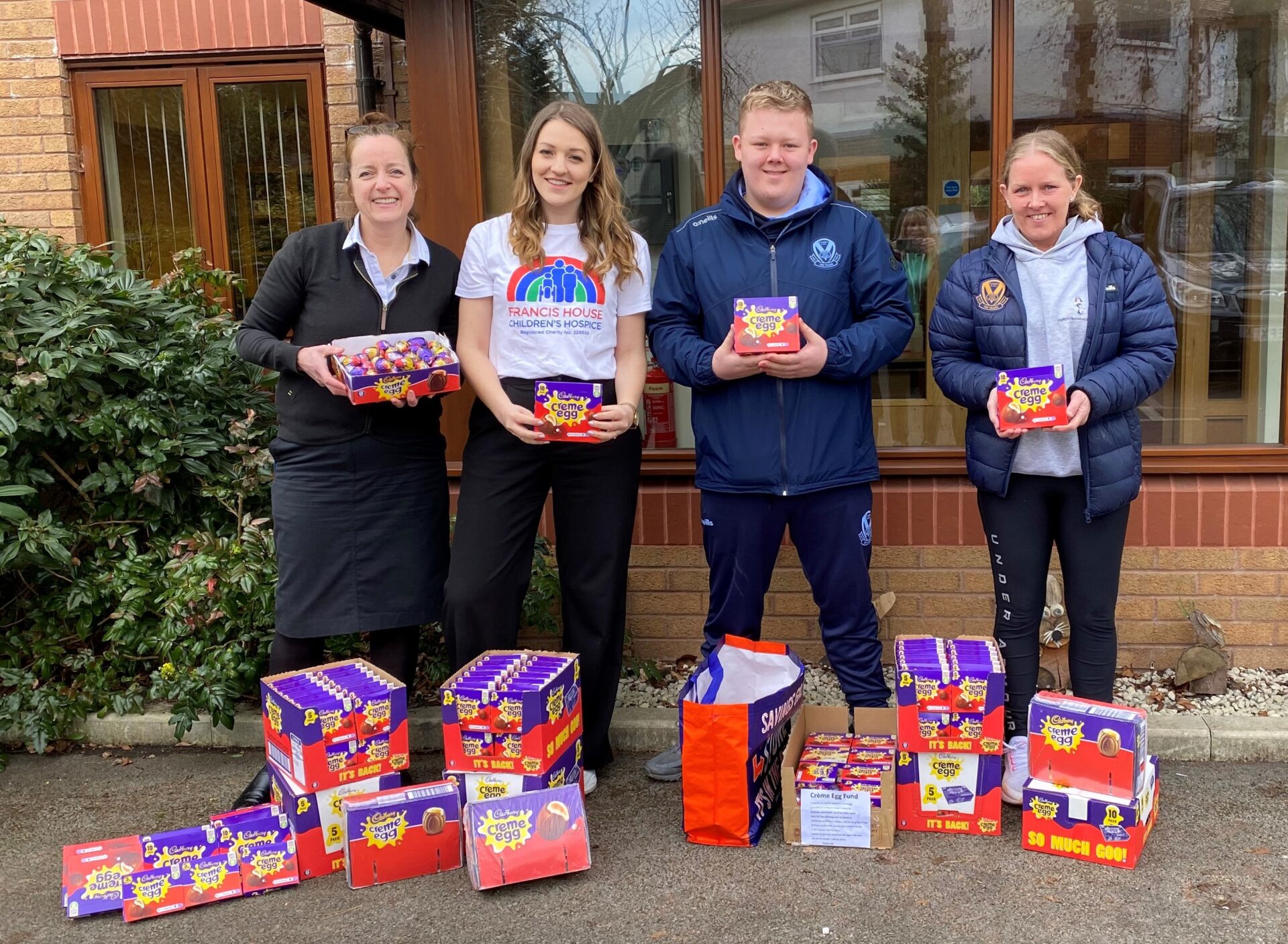 Four people stood behind boxes of chocolate eggs