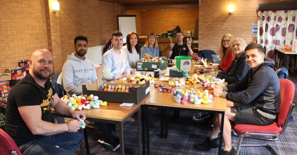 Group of people sat around tables of knitted chicks
