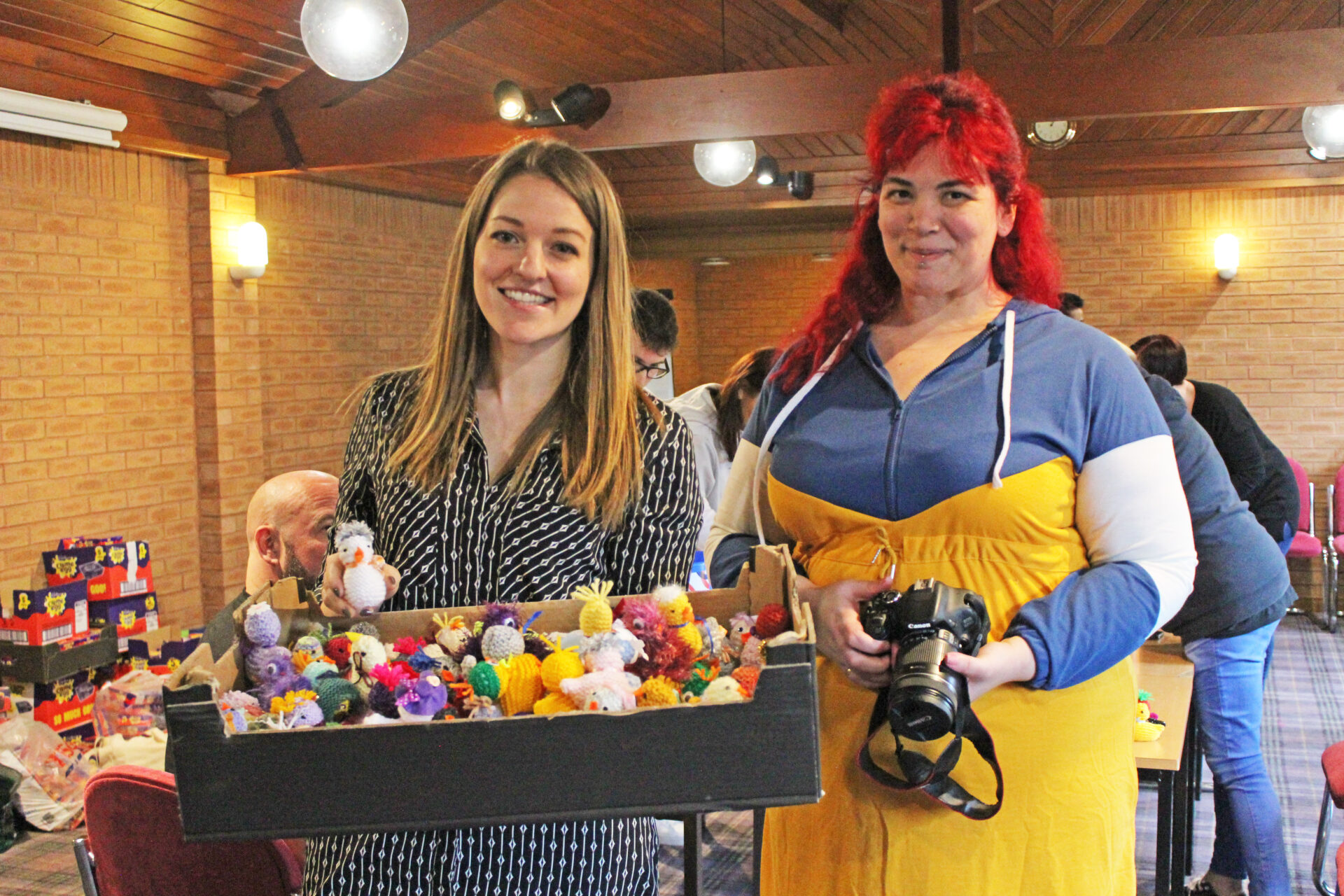 Two women holding a box of knitted chicks