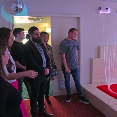 People looking at a sensory room with different coloured lighting
