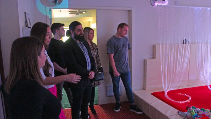 People looking at a sensory room with different coloured lighting