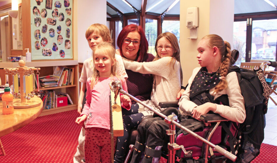 Woman and four young children one child is seated in a wheelchair