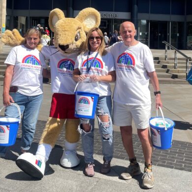 Group of people stood with a mouse mascot holding collection buckets