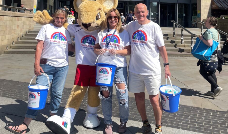 Group of people stood with a mouse mascot holding collection buckets