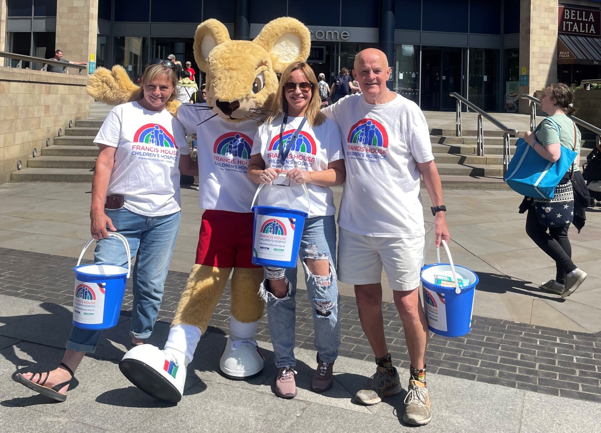 Group of people stood with a mouse mascot holding collection buckets