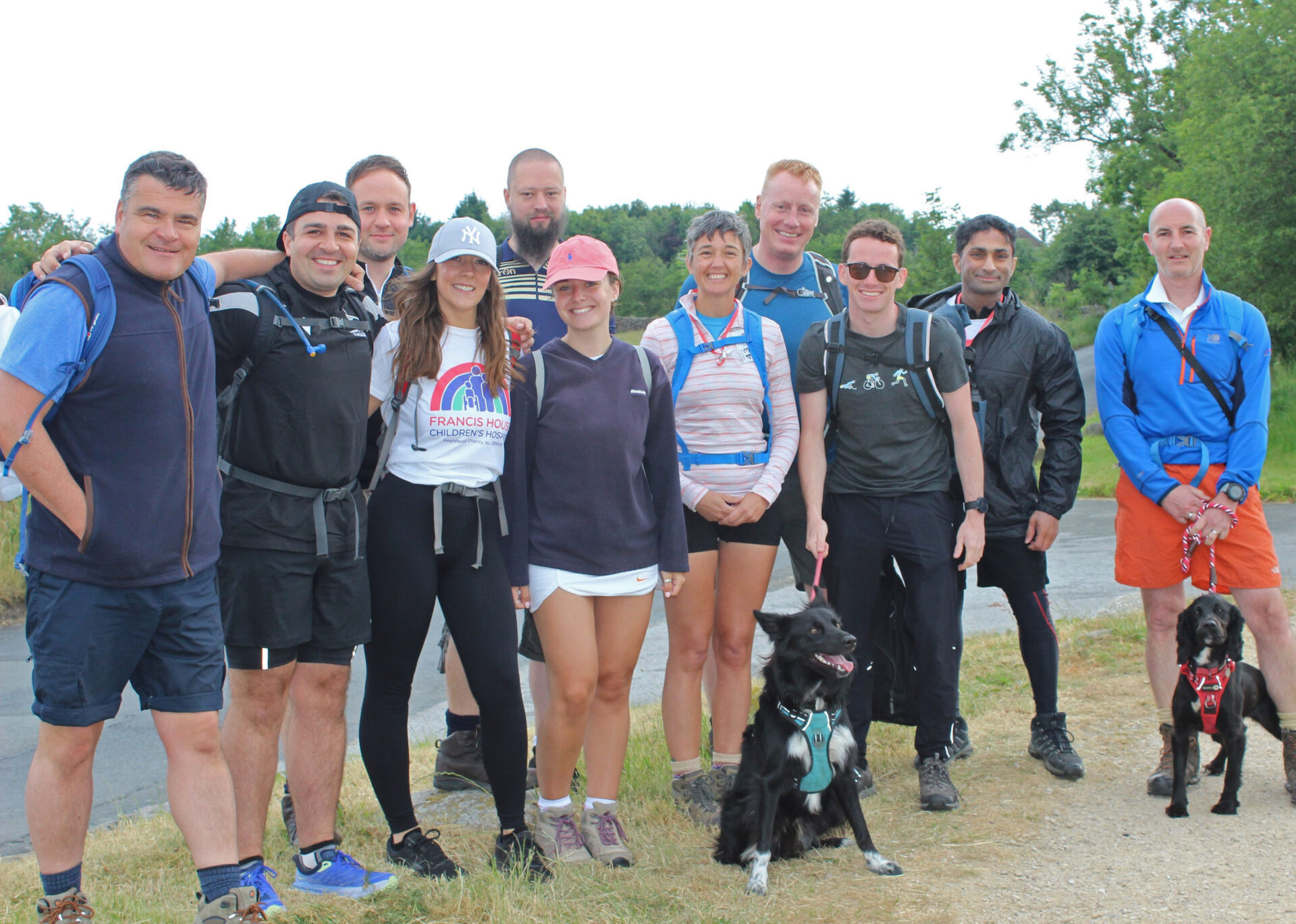 Group of people and dogs wearing hiking gear stood in the countryside