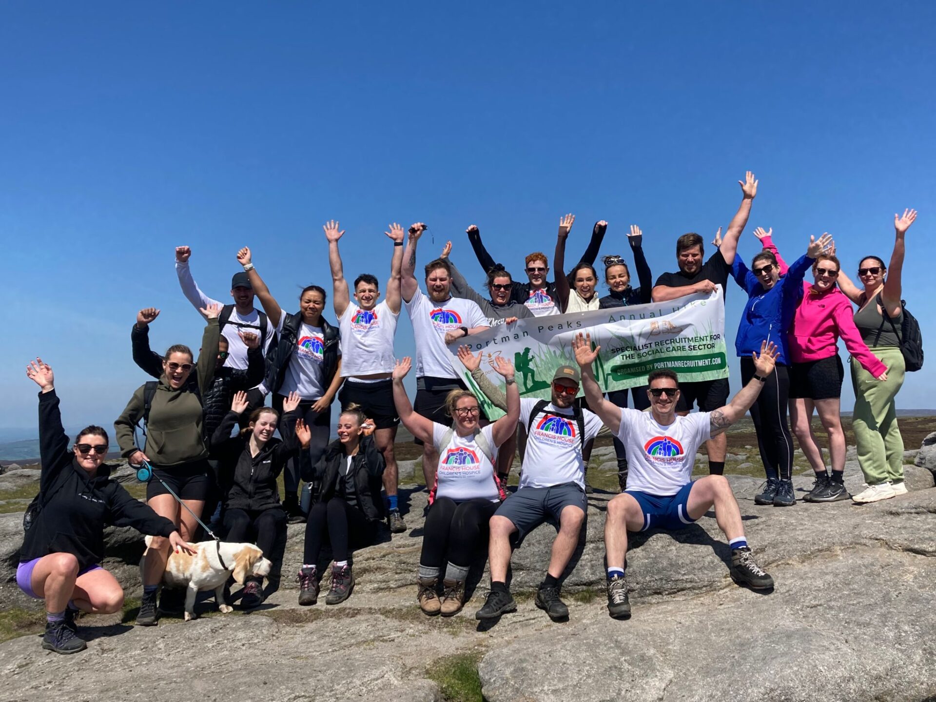 Group of people waving stood at the top of a rocky hill