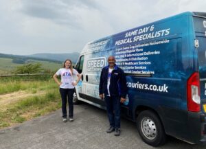 Two people stood next to a van parked on a country road