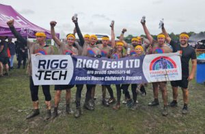 People wearing muddy t-shirts holding a banner raising their arms in the air