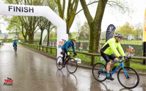 Cyclists cross the finish line at the 2023 Tour de Manc