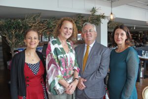 Three women and a man wearing smart clothing stood in a restaurant