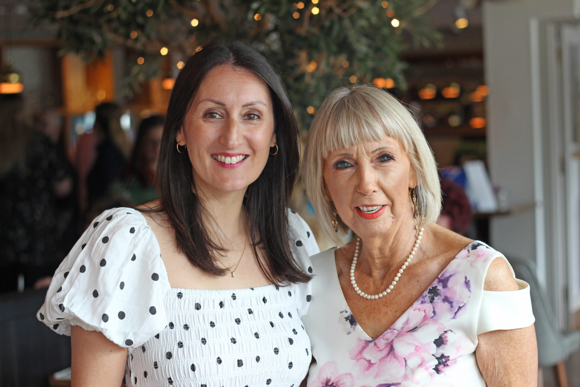 Two women stood in a restaurant with sparkling lights behind them