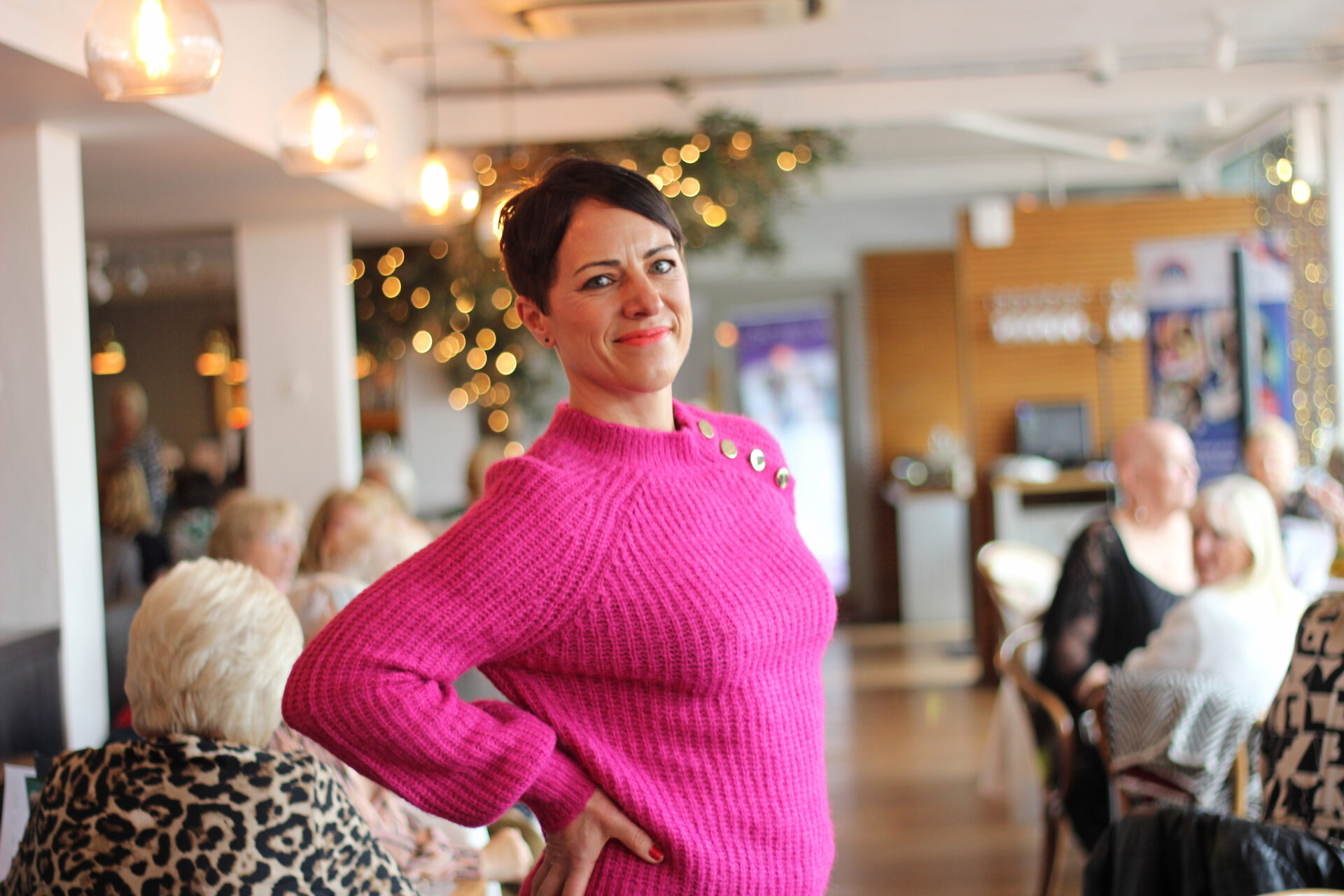 Woman wearing a bright pink jumper stood in a restaurant