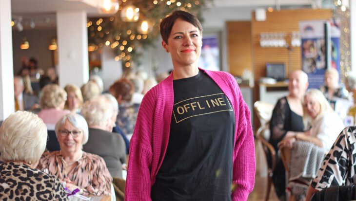 Woman wearing a pink cardigan and black t-shirt stood in a restaurant