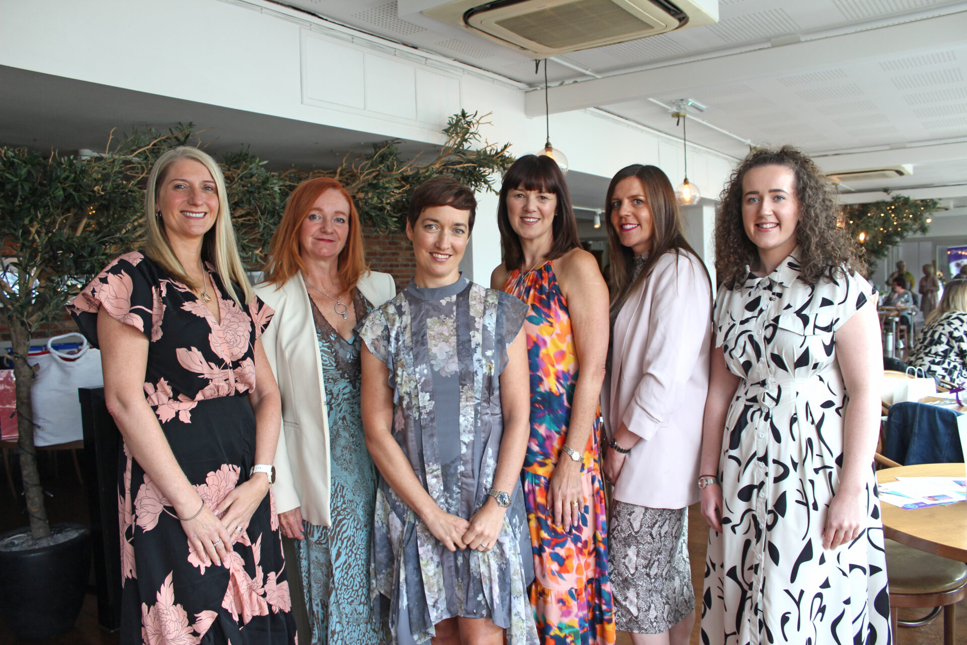 Six women wearing party dresses stood in a restaurant