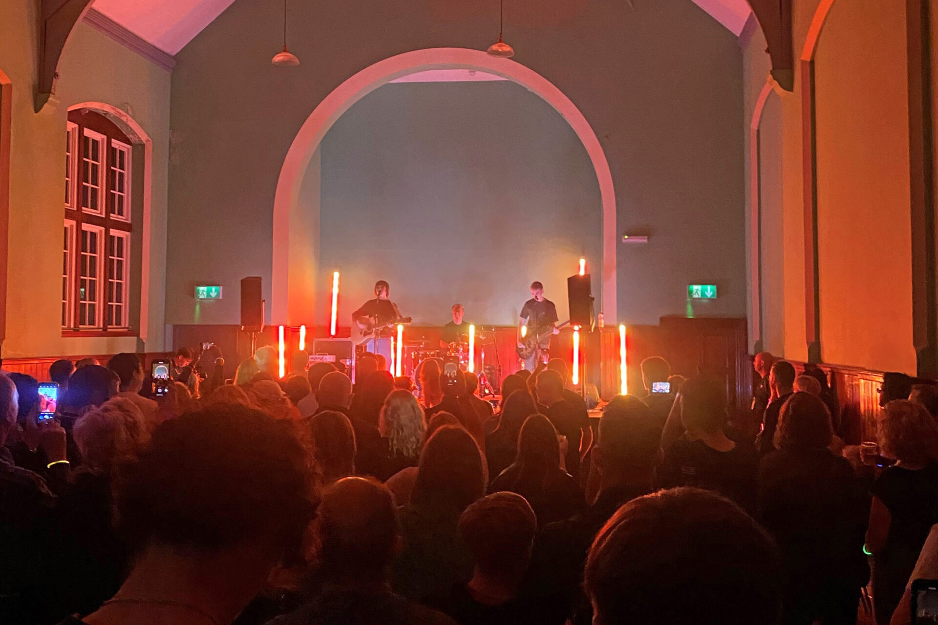 Three members of a band performing on a stage in front of a crowd