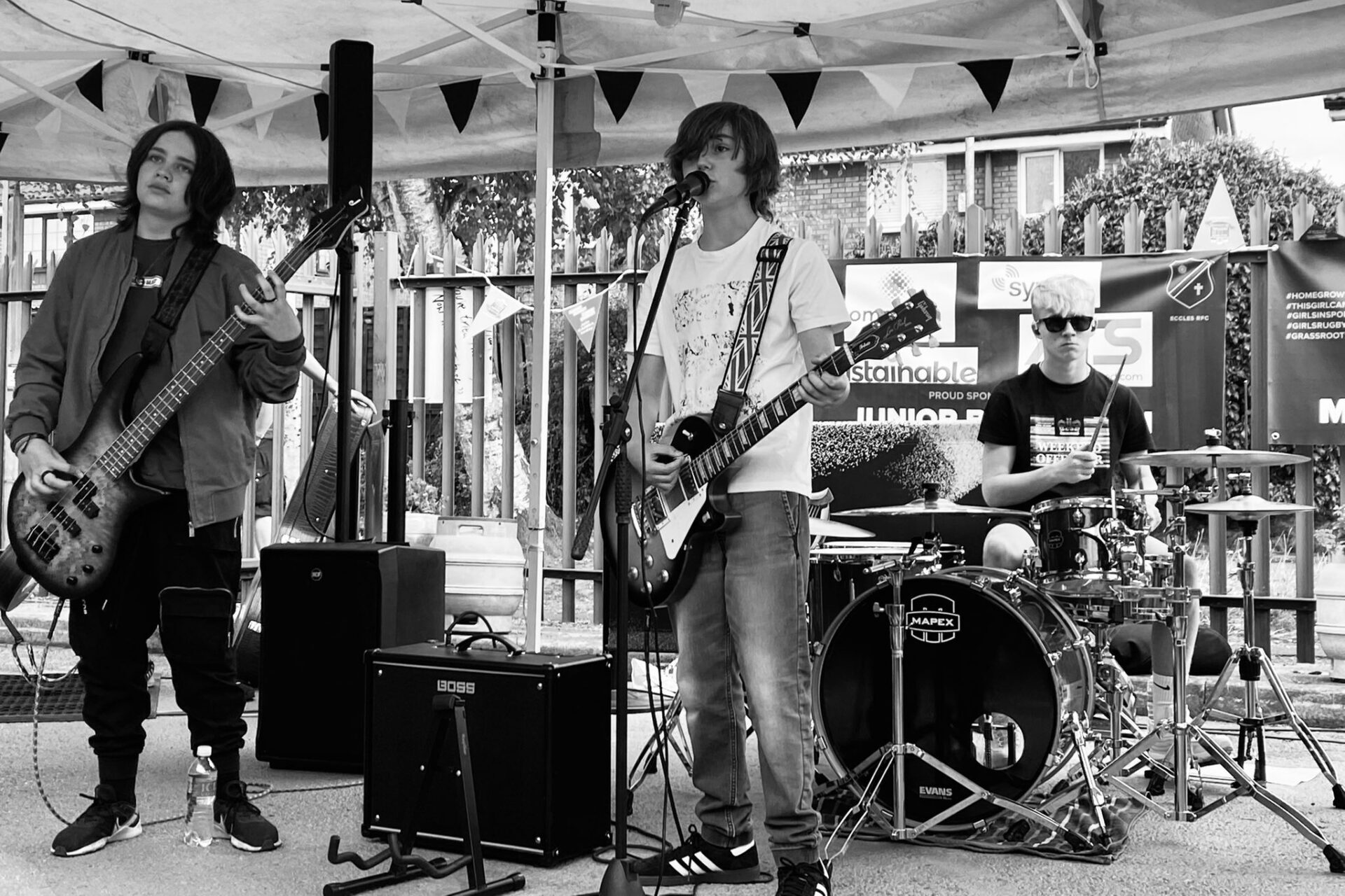 Black and white photo of teenage band members performing on a stage