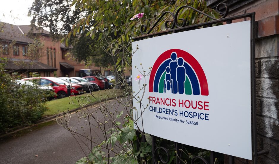 Entrance gates with Francis House signage and building and carpark in the background