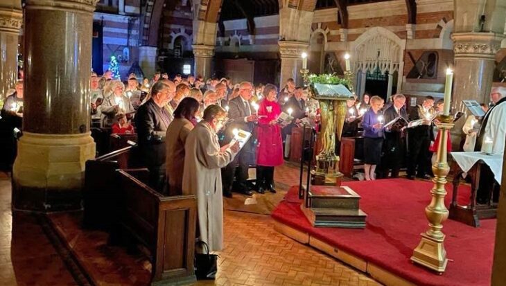 People stood in a church holding candles and singing carols.