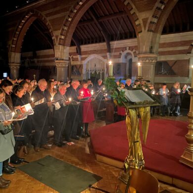 People holding candles and hymn sheets singing in a church