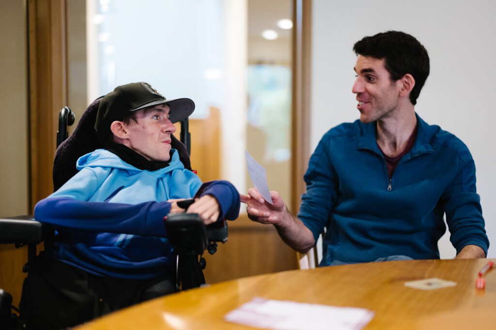 Two people playing a card game looking at each other smiling