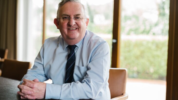 David Ireland sat at a table wearing a shirt and tie