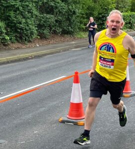 Man wearing a yellow running vest running down a street