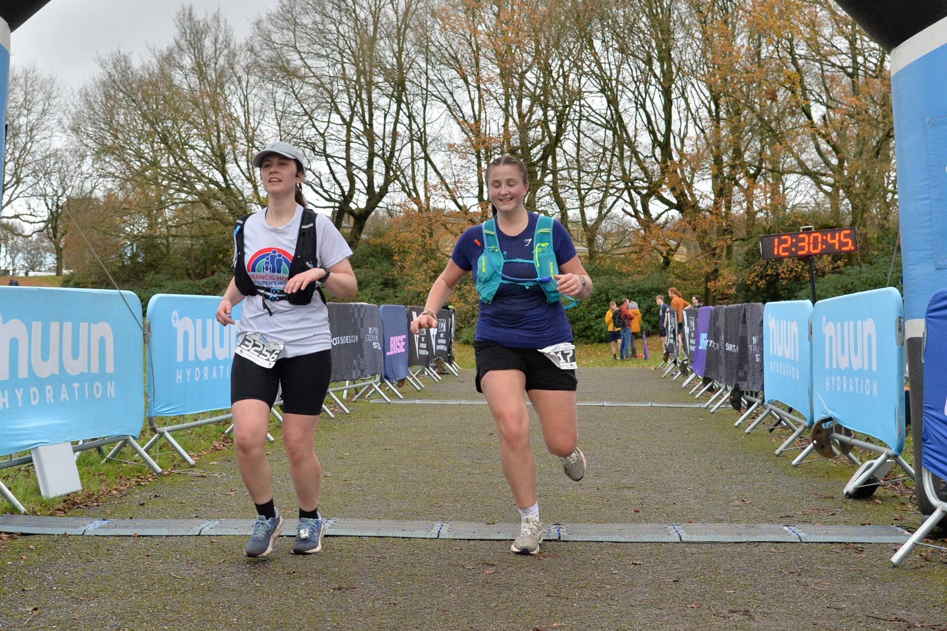 Two female runners smiling crossing the finish line